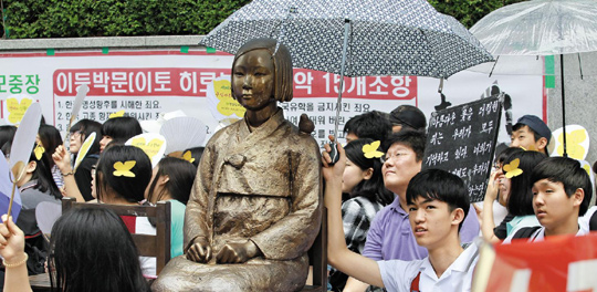 주한 일본 대사관 앞에서는 수요일마다 일본군위안부 문제 해결을 촉구하는 집회가 열려요. 집회에 참여한 한 학생이 일본 대사관 앞에 설치된‘평화의 소녀상’에 우산을 씌워 주고 있어요.