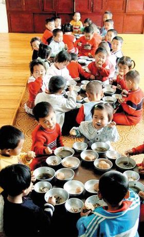 평양 교외의 한 탁아소에서 북한 어린이들이 큰 상 앞에 둘러앉아 점심을 먹는 모습이에요.
