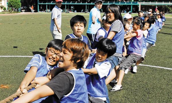 한 초등학교의 가을 운동회에서 학생들이 힘껏 줄다리기를 하고 있어요.