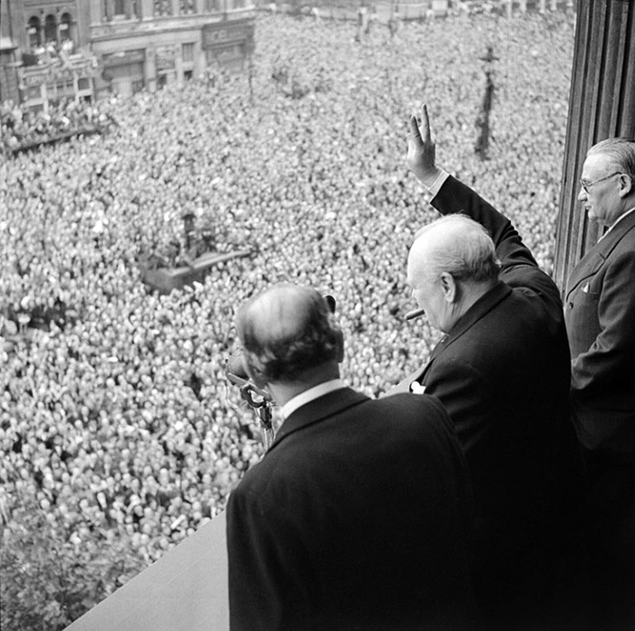 독일이 항복한 1945년 5월 8일 런던 화이트홀 한 건물에서 군중을 향해 ‘승리의 V’ 사인을 보내는 윈스턴 처칠(오른쪽)의 모습. 그는 취임 직후 “내가 (국민에게) 드릴 수 있는 건 피와 땀, 수고, 눈물밖에 없다”는 내용의 연설을 했어요. /위키피디아