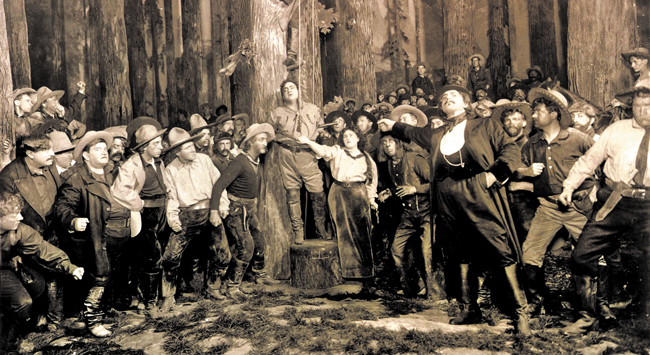 1910년 미국 뉴욕에서 초연한 오페라 '서부의 아가씨'의 한 장면. 극 중에서 교수형을 앞두고 나무 밑동 위로 올라선 엔리코 카루소(딕 존슨 역). 그 오른편으로 순서대로 에미 데스틴(미니 역)과 파스콸레 아마토(잭 랜스 역)예요. /메트로폴리탄 오페라 아카이브