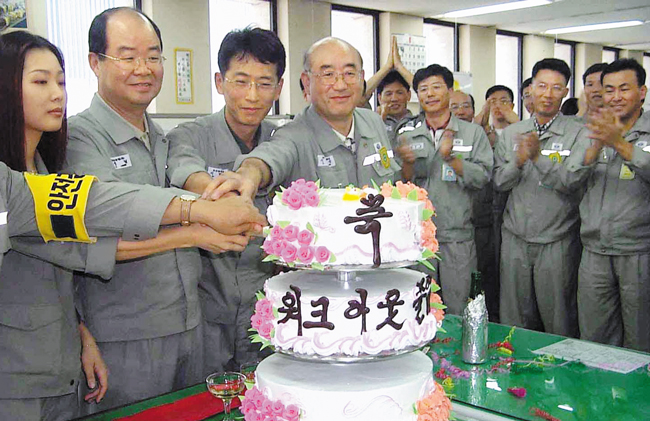 2001년 8월 23일 대우조선 옥포조선소(현 한화오션 거제사업장)에서 당시 임직원들이 워크아웃 졸업을 축하하는 케이크를 자르고 있어요. /연합뉴스