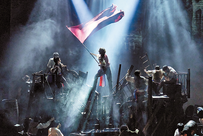 뮤지컬 ‘레 미제라블’ 공연에서 사다리와 수레 등으로 쌓아올린 바리케이드 위에 시민군을 연기하는 배우들이 올라서서 혁명을 상징하는 깃발을 흔들고 있어요. /레미제라블코리아