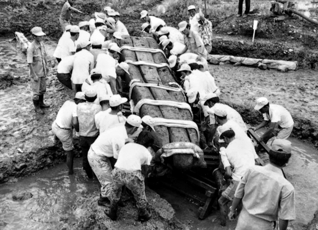 1975년 월지 발굴 현장에서 발견된 나무배를 인부 수십 명이 옮기고 있는 모습. /국립경주문화재연구소
